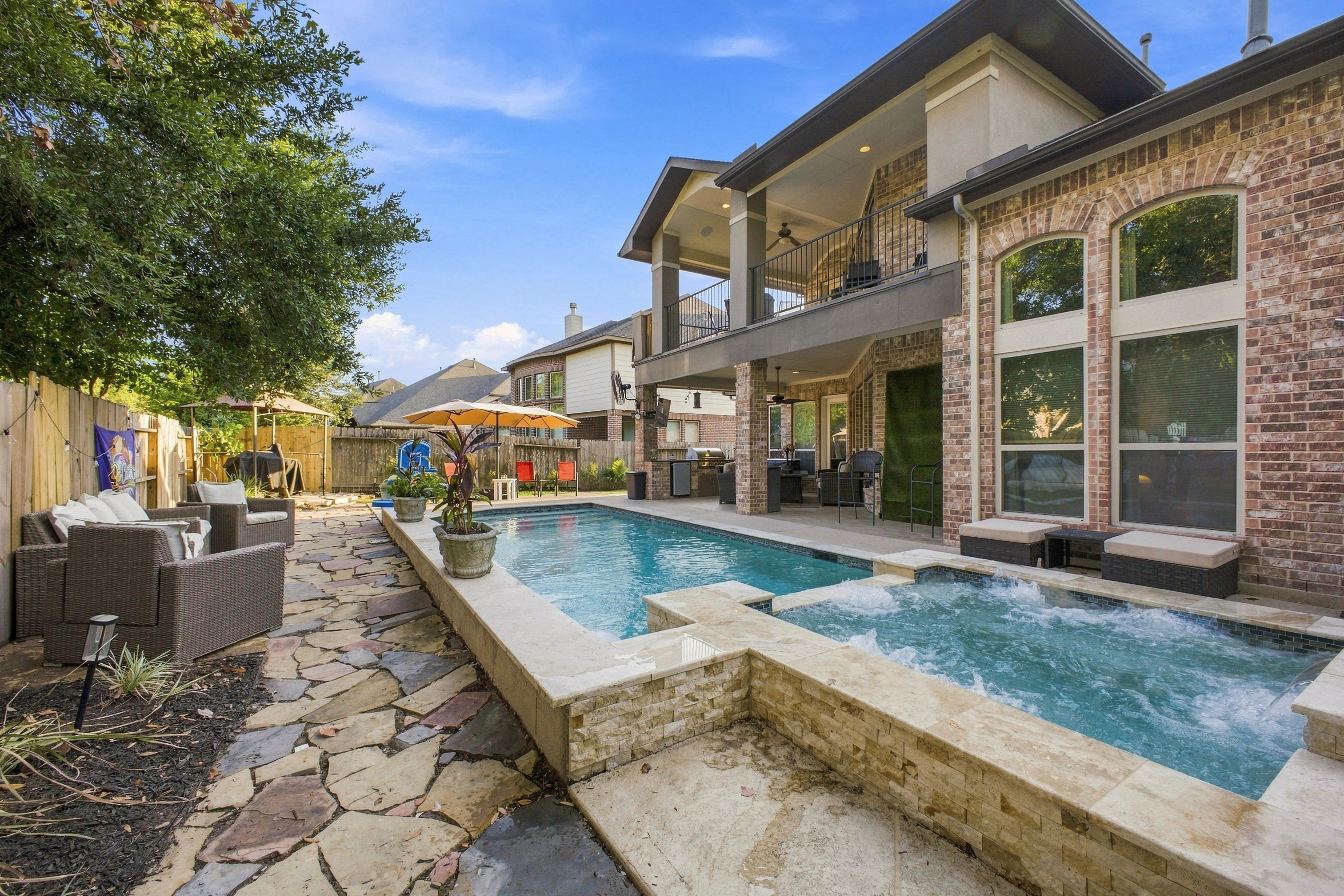 Backyard space with pool and jacuzzi overlooked by master bedroom balcony